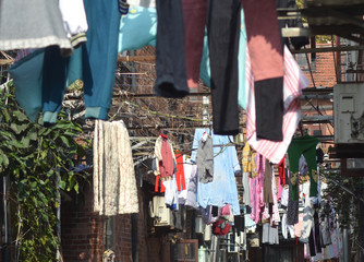 Clothes have been hung to dry between the buildings of a back street in Shanghai. Air conditioning units can also  be seen.