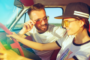 Laughing romantic couple sitting in car while out on a road trip at summer day