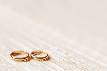 Obraz na płótnie Canvas Golden wedding rings on beige fabric background. Wedding details, symbol of love and marriage.