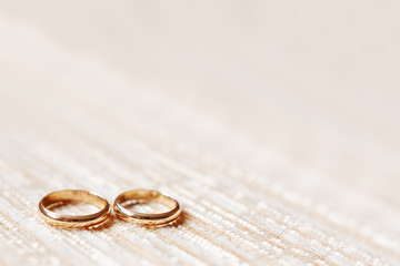 Golden wedding rings on beige fabric background. Wedding details, symbol of love and marriage.