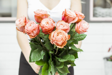 Young woman holding bouquet of pink roses at the street