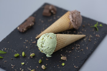 Chocolate and pistachio ice cream in waffle cones, with nuts and pieces of dark chocolate.