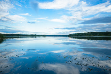 view of the river from the shore with a beautiful sky and clouds