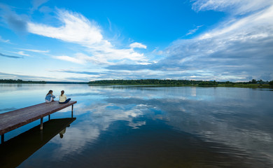 Obraz premium silhouettes of girls sitting on a bridge by the river