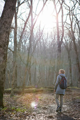 Obraz premium The girl in the grey jacket and with a rucksack on his back walks in the morning in the autumn forest.