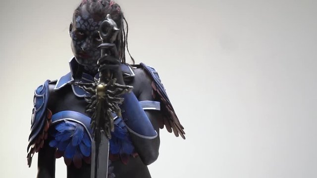 A drow woman with white eyes staring intently at the camera posing with a sword, slow motion