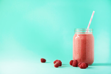 Pink raspberries smoothie or milk shake in glass jar with berries background. Banner, copy space....