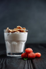 homemade yoghurt with flakes and raspberries on  dark wooden background