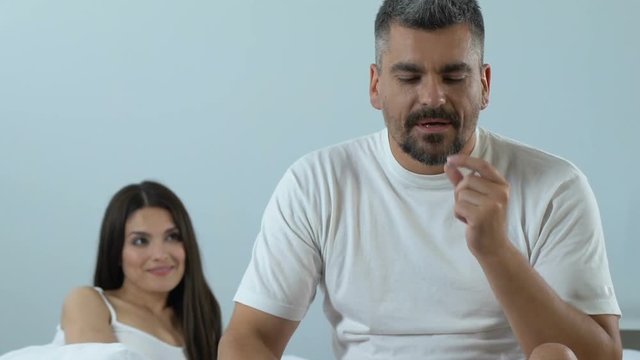 Handsome lover taking pill before sex and showing silence sign, mens health