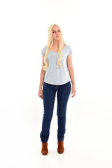 Obraz premium full length portrait of blonde girl wearing blue shirt and jeans, standing pose isolated on white studio background.