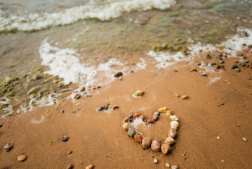 Heart shape from sea stones on a sandy ocean beach, top view, copy space. Love summer vacation background, romance concept