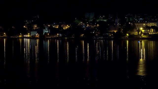 Сity light reflections at the water of Kotor Bay by night. Montenegro