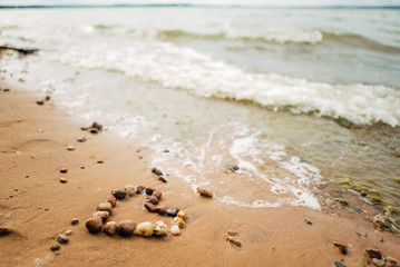 Heart shape from sea stones on a sandy ocean beach, top view, copy space. Love summer vacation background, romance concept