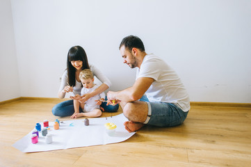 Happy family sketching on paper at parquet floor with a cat