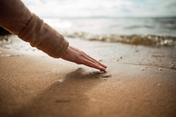 Woman hands in water inviting you over sunset golden rays.