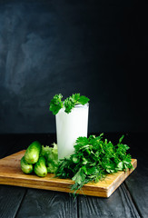 Fresh plain homemade yougurt with cucumber herbs over dark background, probiotic cold fermented dairy drink.