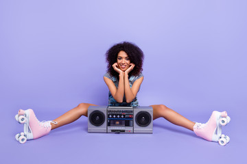 Portrait of stylish trendy girl having portable boom box having rest break after riding on roller skates listening favorite song isolated on bright violent background. Culture concept © deagreez