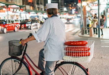 Cyclist on a city street at night, Kyoto in Japan. Close-up. Back view..