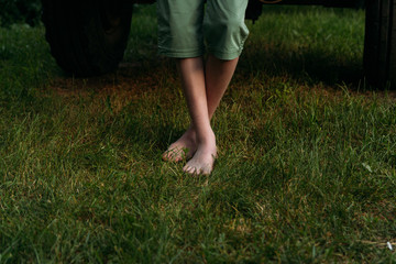 Obraz na płótnie Canvas Foot over green grass. bare feet to stand on the green grass. in green shorts near the car