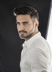 Obraz premium Head and shoulders shot of handsome young man with elegant shirt, looking at camera, on dark background