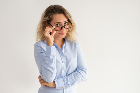 Serious Snippy Business Lady Looking Over Her Glasses. Arrogant Attractive Lady In Blue Blouse Adjusting Eyewear And Looking At Camera. Teacher Concept