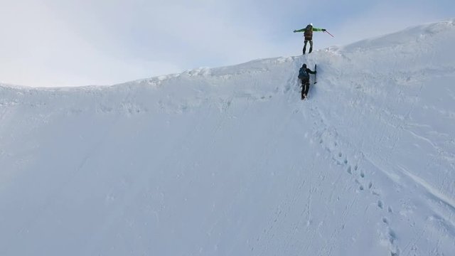 Stunning aerial drone footage of two hikers on a mountain ridge (arete) near the summit of Aletschhorn mountain in the Bernese Alps, Switzerland. Ebnefluh and Gletscherhorn mountains in background.