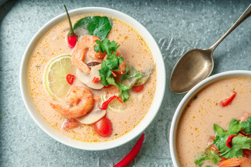 Traditional thai soup tom yum with shrimps and mushrooms, served with fresh lime slices on metallic tray