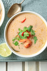 Traditional thai soup tom yum with shrimps and mushrooms, served with fresh lime slices on metallic tray