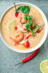 Traditional thai soup tom yum with shrimps and mushrooms, served with fresh lime slices on metallic tray