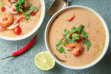 Traditional thai soup tom yum with shrimps and mushrooms, served with fresh lime slices on metallic tray