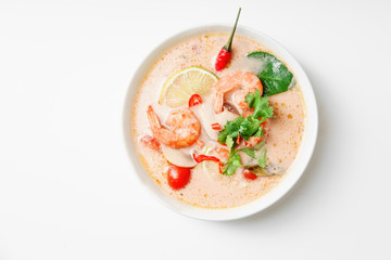Traditional thai soup tom yum with shrimps and mushrooms, served with fresh lime slices. Top view, white background