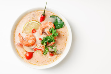 Traditional thai soup tom yum with shrimps and mushrooms, served with fresh lime slices. Top view, white background