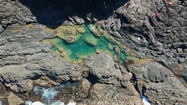 Stunning wide angle aerial drone view of the Mermaid Rock Pools and ocean waves at Matapouri Bay near Whangarei on the North Island of New Zealand. The rock pools are a popular tourist destination.