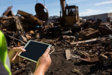 Worker holding digital tablet in the scrapyard