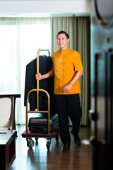 Fototapeta na wymiar Portrait of bell boy pulling box van in Asian hotel