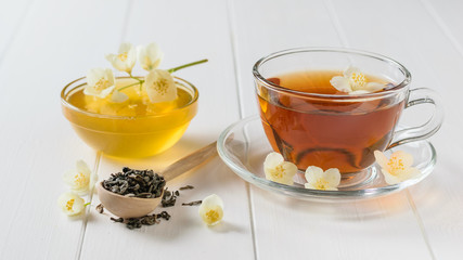 Freshly prepared tea with Jasmine flowers and honey on a table.