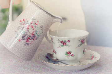 Pouring milk to coffee cup.