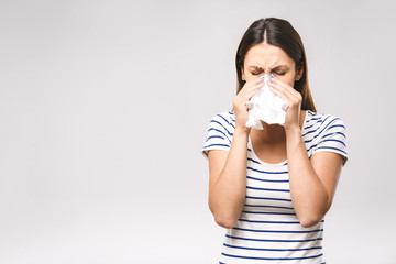 People, healthcare, rhinitis, cold and allergy concept - unhappy woman with paper napkin blowing...