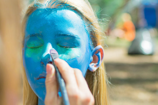 The girl's face is completely painted blue with aqua-grime. Festive preparation.