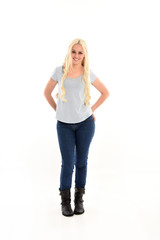 full length portrait of blonde girl wearing blue shirt and jeans, standing pose isolated on white studio background.