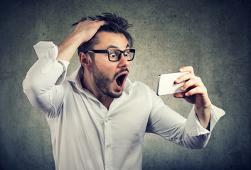 Shocked man watching phone and pulling out hair - obrazy, fototapety, plakaty