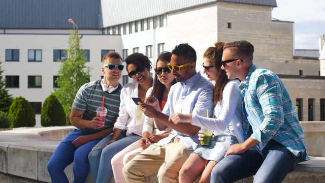 technology, friendship and international concept - group of students or friends with drinks and smartphone in city