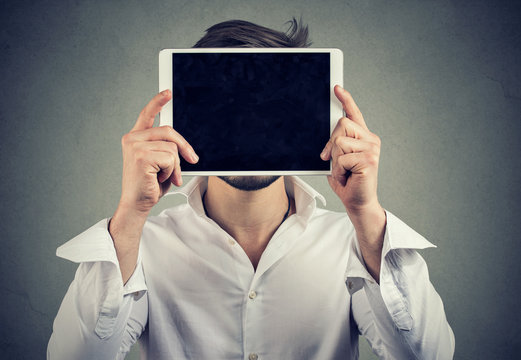 Anonymous man covering face with tablet computer