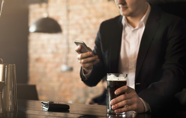 Young man sitting at bar counter and using smartphone