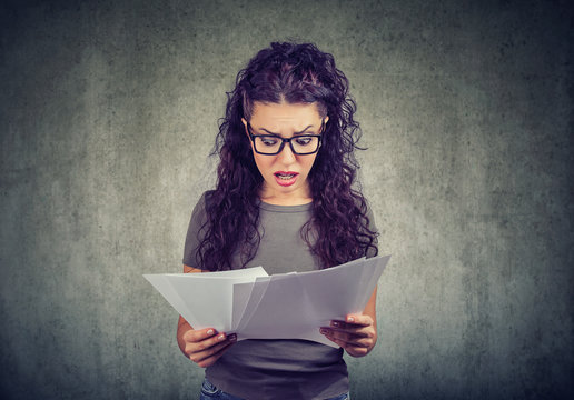 Shocked woman looking through papers with bills