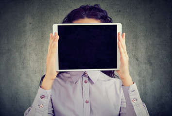 Anonymous woman covering face with tablet