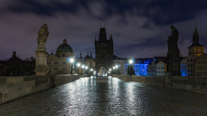 Fototapeta na wymiar Karlsbrücke in Prag über die Moldau am Morgen. Nasses Kopfsteinpflaster.