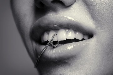 Accessories. Woman with piercing in mouth. Open lips with metal ring between teeth. Fun expression...