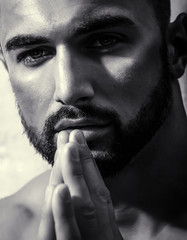 Man portrait. Close-up of a man's face. Portrait of young man praying. Topless handsome guy keeps hands together in front of his sensual lips. Seductive pose of good-looking male model. Praying prist - 212769445