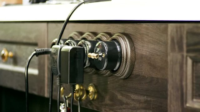 Three electric plugs into the socket. Close-up shot of electrical outlets, cable on wooden chest. 4K